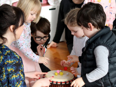 Children surround drum with ELC music class teacher